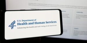 HHS logo on phone screen by laptop