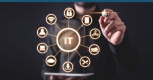 Image of a circles in the shape of a wheel with IT in the middle circle and icons for various information technology items in the other circles such as website, lock, and download icons. Behind the wheel circle is an image of a man holding a tablet pen.